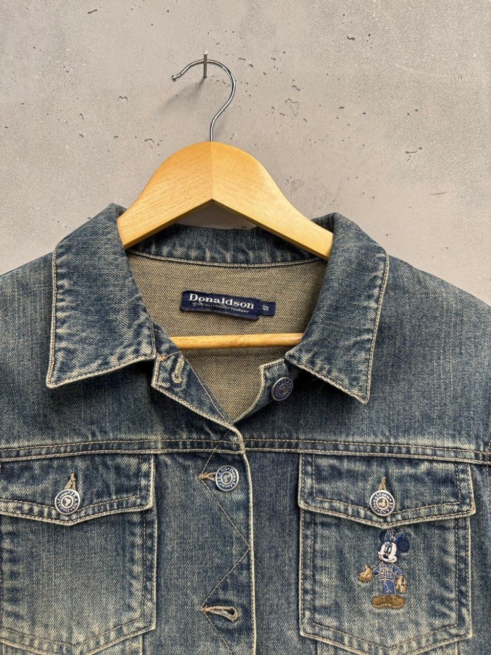 BERLIN VINTAGE CORNER blue washed denim jacket with embroidered Mickey Mouse motif on chest pocket. Classic trucker style with button front.