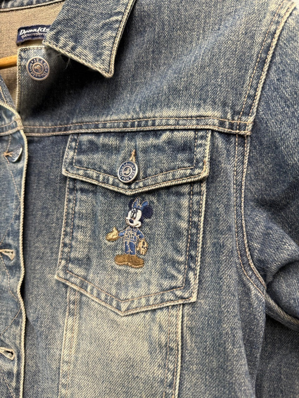 BERLIN VINTAGE CORNER blue denim jacket with embroidered Mickey Mouse on chest pocket. Classic trucker style with button front.
