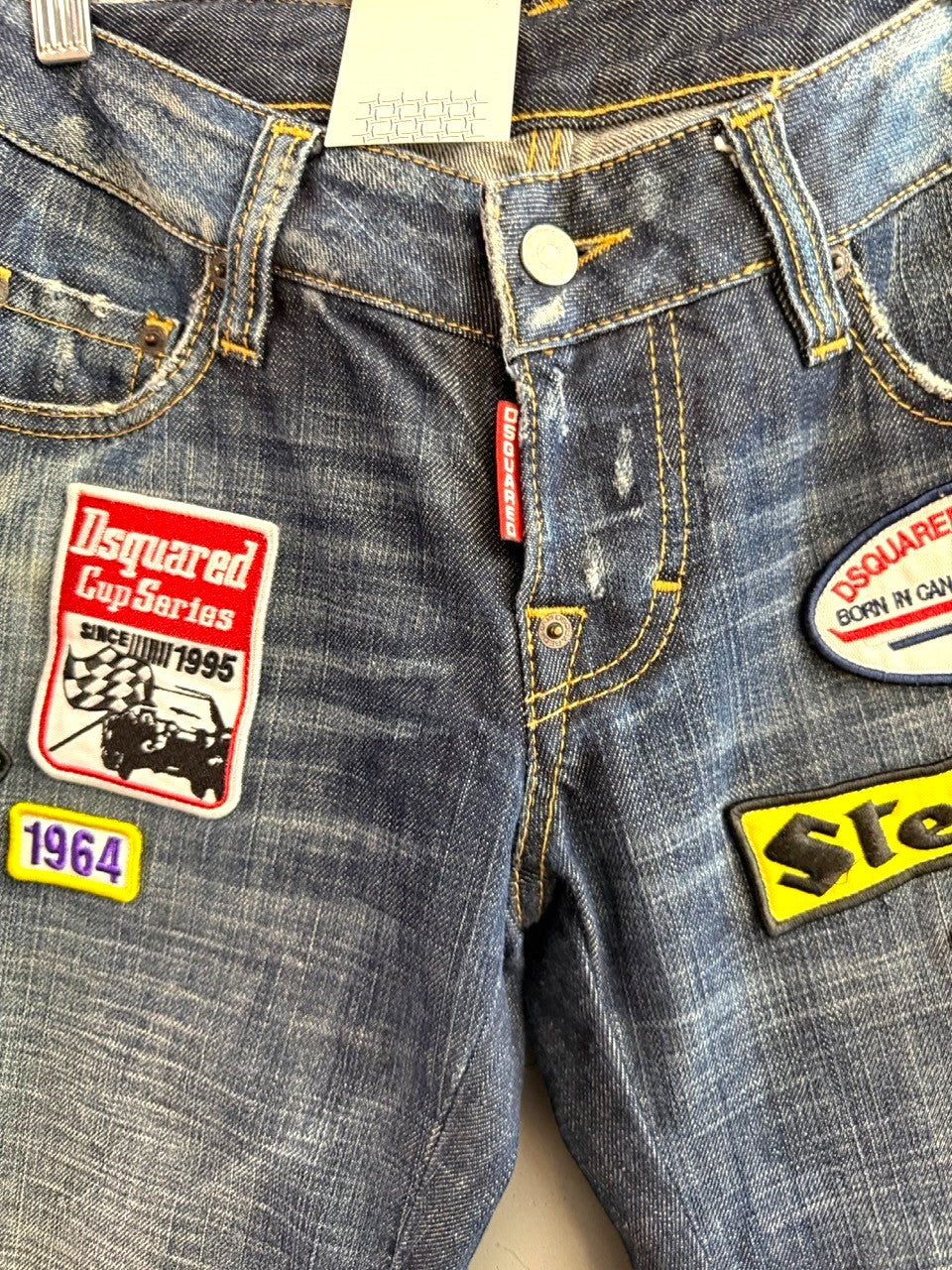 BERLIN VINTAGE CORNER blue denim jeans with distressed finish and embroidered patches including "Dsquared Cup Series" and "Steer."