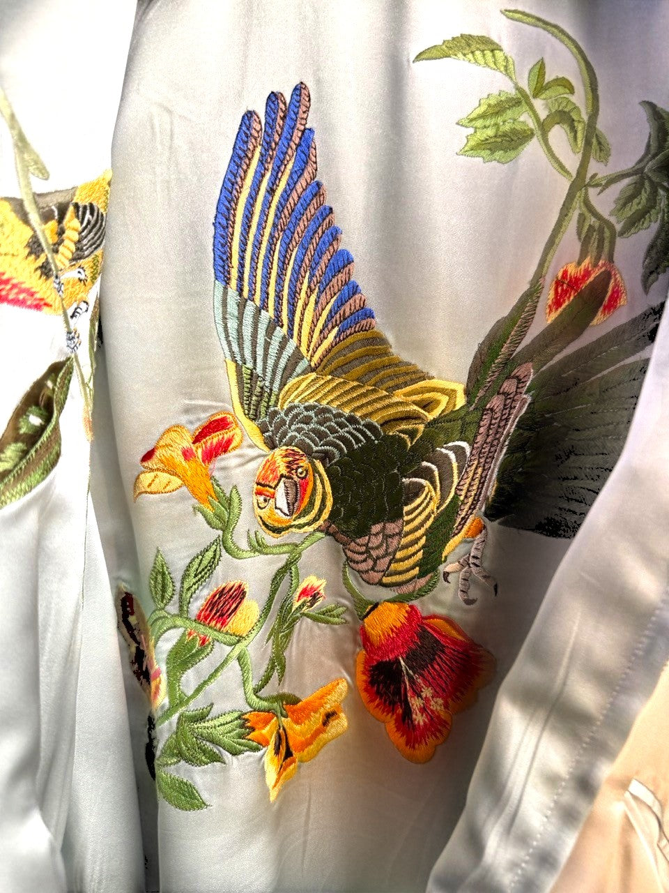 BERLIN VINTAGE CORNER champagne satin bomber jacket with embroidered birds and flowers. Features ribbed collar, cuffs, and hem.