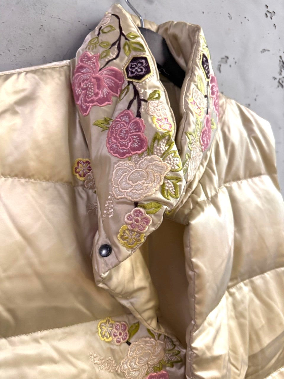 BERLIN VINTAGE CORNER champagne satin puffer vest with intricate multi-colored floral embroidery and snap-button collar.