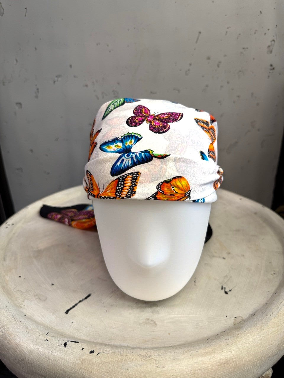 BERLIN VINTAGE CORNER ESCADA silk scarf featuring a vibrant butterfly print on a white background on a mannequin head