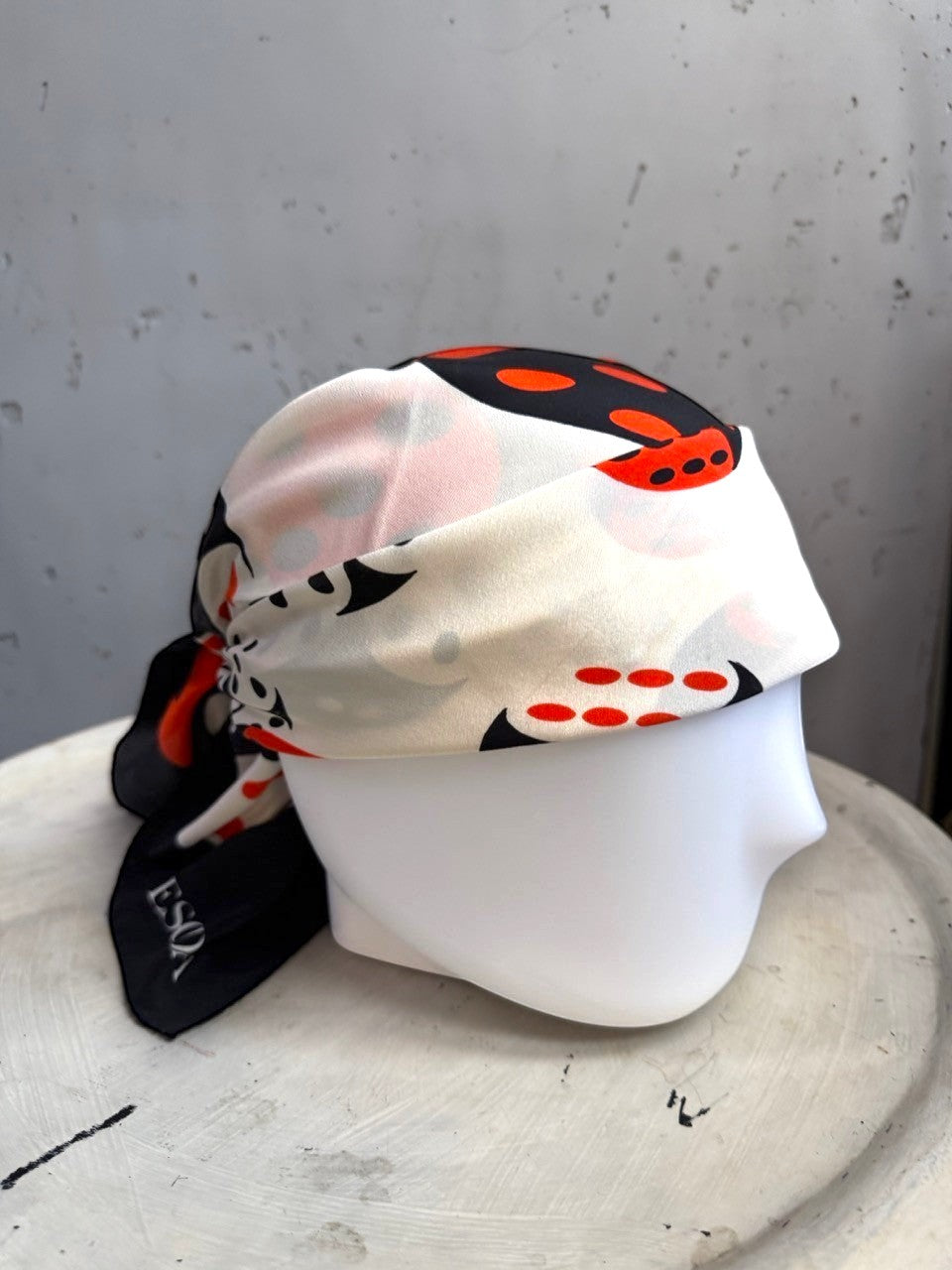 BERLIN VINTAGE CORNER Escada silk scarf with black, white, and red dice print styled on a mannequin head.