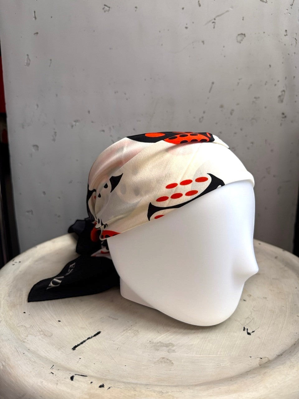 BERLIN VINTAGE CORNER ESCADA silk scarf with black, white, and red dice print styled on a mannequin head