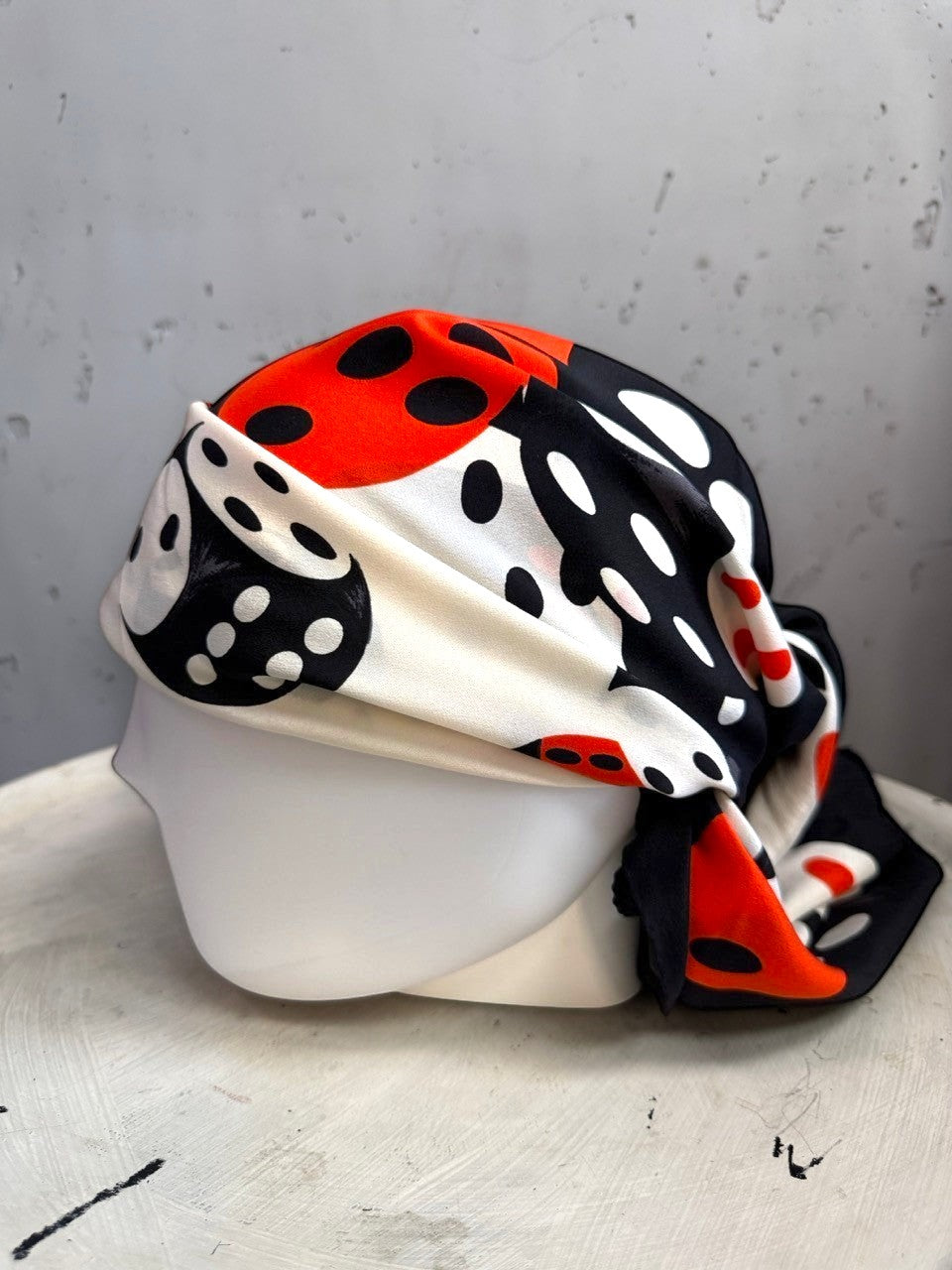 BERLIN VINTAGE CORNER Escada silk scarf with a bold black, white, and red dice print styled as a headscarf on a mannequin