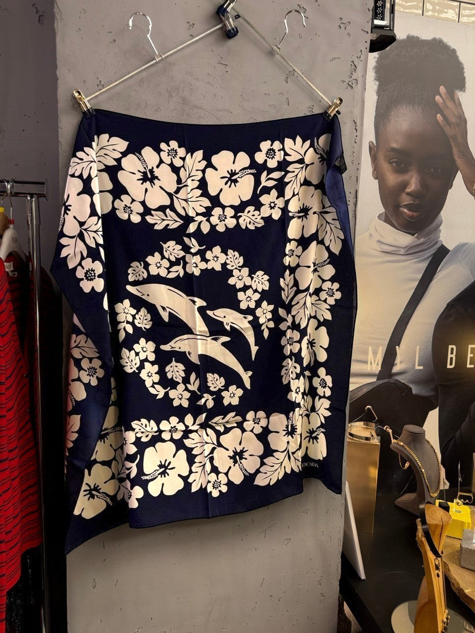 BERLIN VINTAGE CORNER navy blue ESCADA silk scarf with white floral and dolphin print, hanging in a boutique.