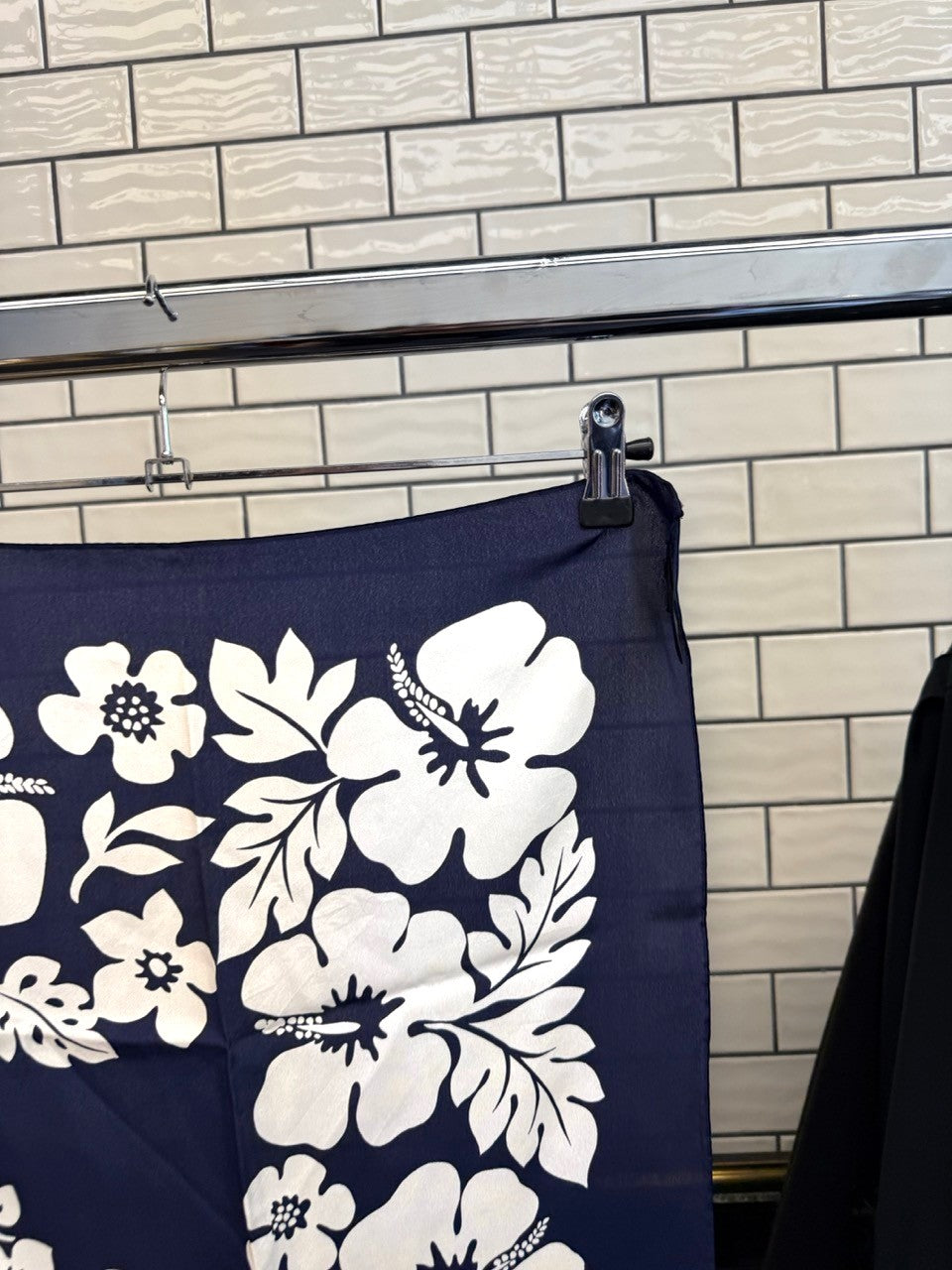 BERLIN VINTAGE CORNER Escada navy blue silk scarf with white hibiscus floral print hanging on a clothing rack