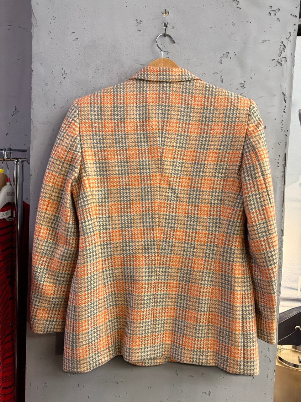 Back view of a BERLIN VINTAGE CORNER Escada Margaretha Ley wool-blend plaid blazer in orange and grey.
