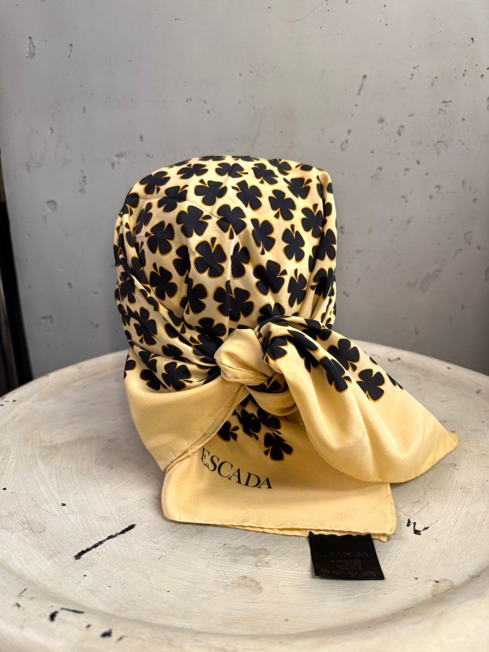 BERLIN VINTAGE CORNER Escada cream silk square scarf with a black clover print tied on a display stand.