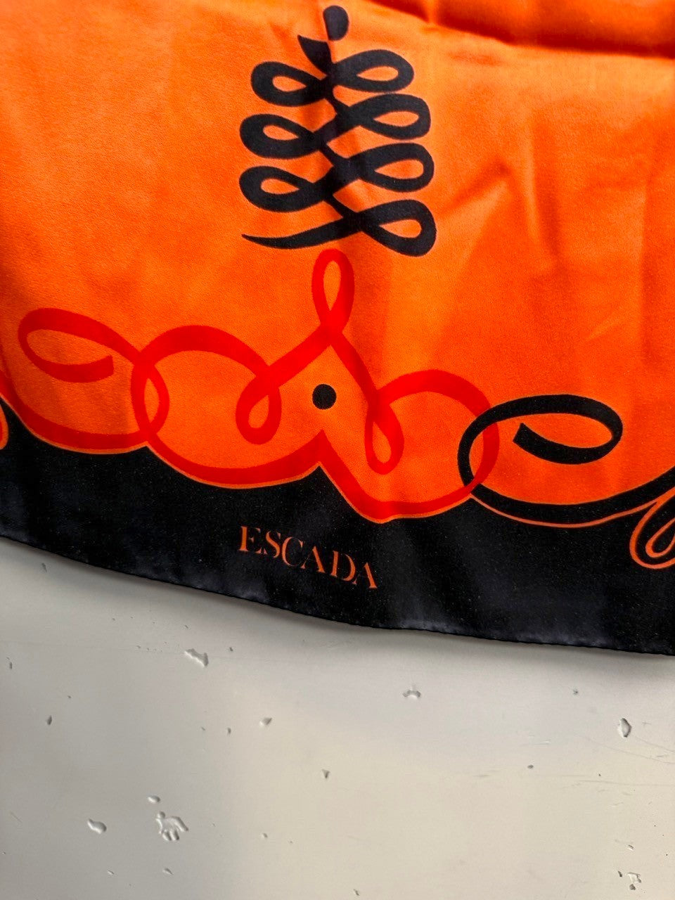 BERLIN VINTAGE CORNER Escada vintage silk scarf in orange and black with ornate scrollwork and designer logo detail.