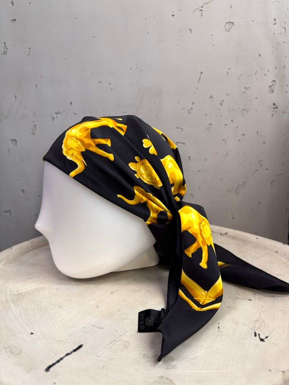 BERLIN VINTAGE CORNER vintage ESCADA silk scarf in black with golden elephant and turtle motif on a mannequin head