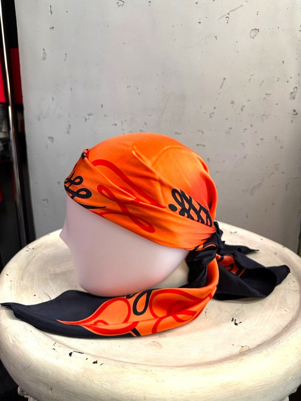 BERLIN VINTAGE CORNER vintage ESCADA silk scarf in vibrant orange and black with ornate scrollwork on a mannequin head