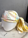 BERLIN VINTAGE CORNER vintage Escada silk scarf with yellow, peach, and sage baroque print on a mannequin head.
