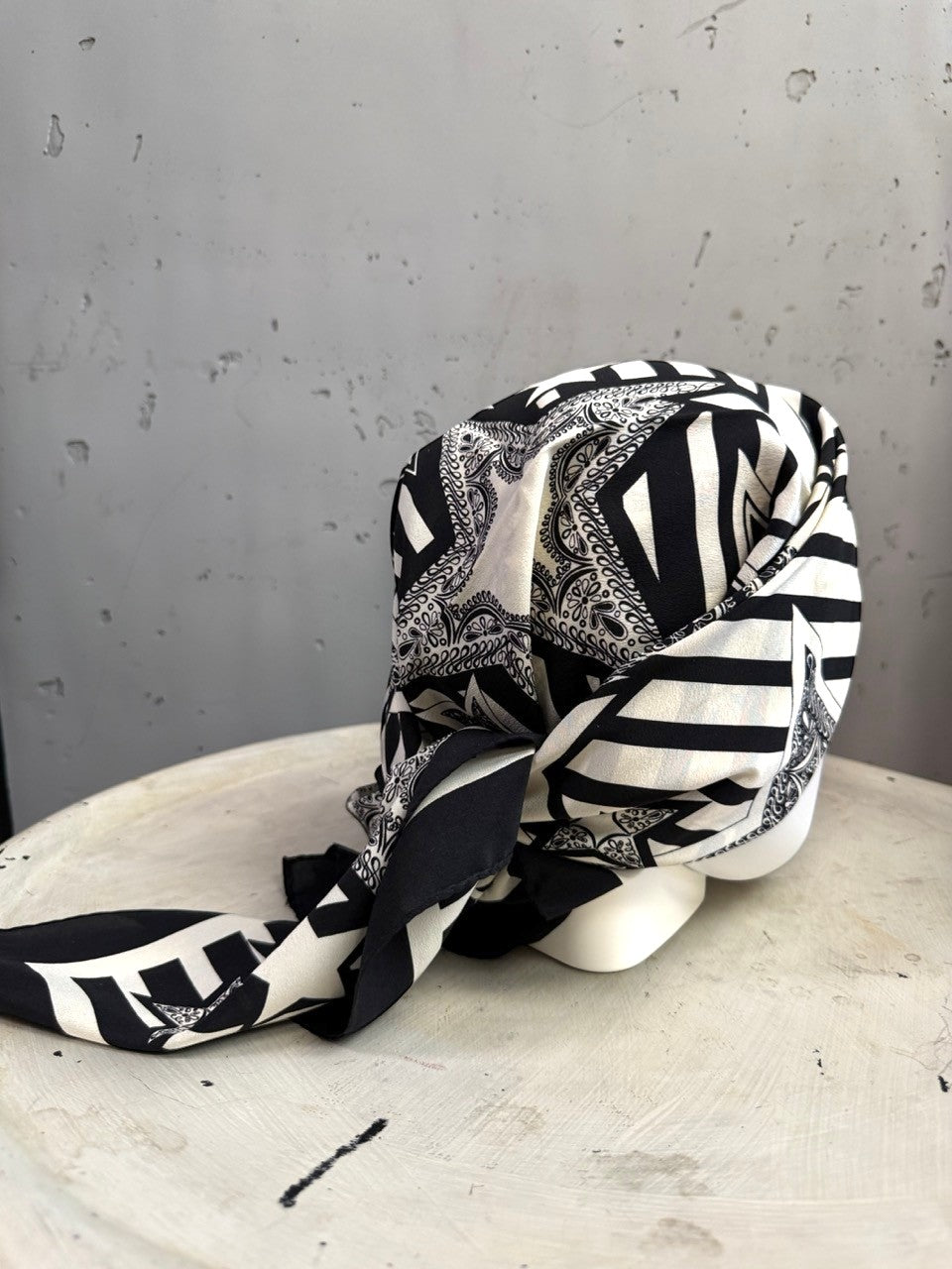 BERLIN VINTAGE CORNER Escada silk scarf in black and white with graphic star and stripe patterns on a mannequin head.