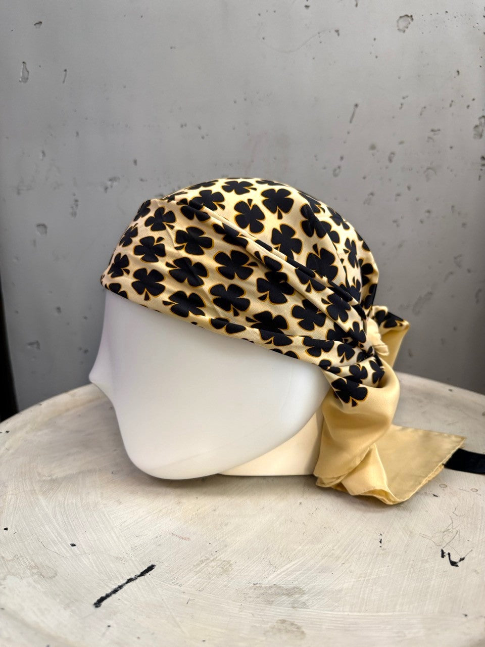 BERLIN VINTAGE CORNER Escada silk square scarf in cream with a black clover print, styled as a head wrap.