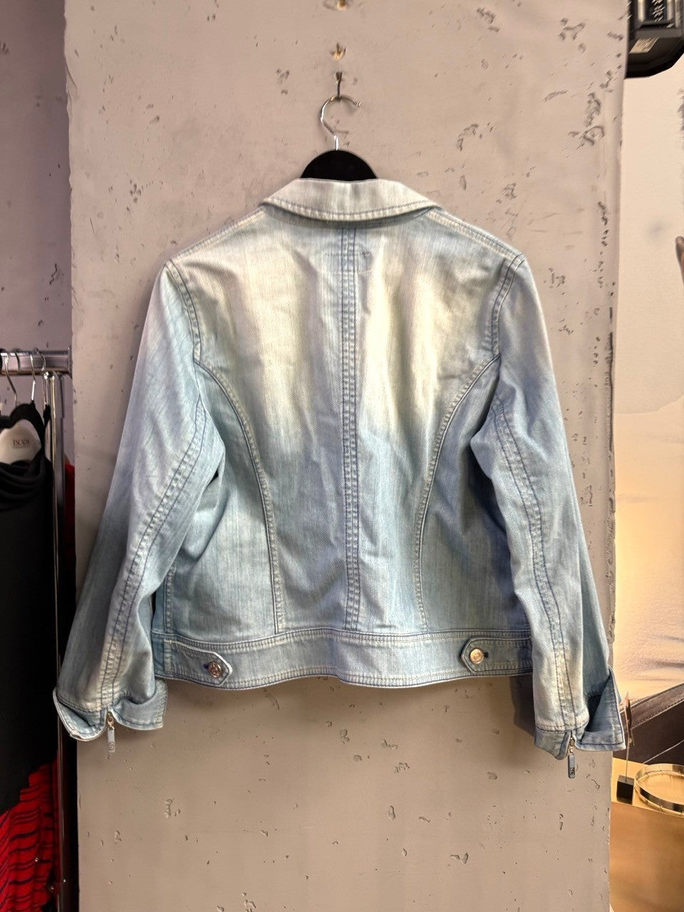 Back view of a light-wash ESCADA SPORT denim jacket with structured seams and zippered cuffs from BERLIN VINTAGE CORNER