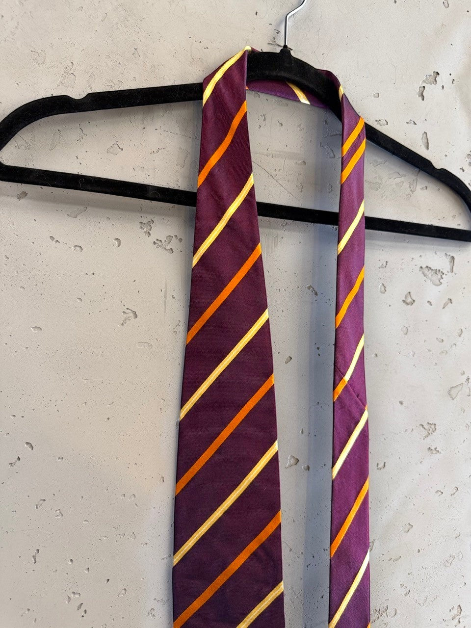 BERLIN VINTAGE CORNER Etro Milano necktie in deep plum with diagonal gold and amber stripes on a black hanger.