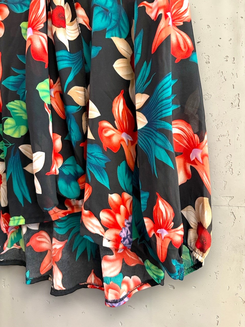 BERLIN VINTAGE CORNER floral print blouse with vibrant tropical flowers on a black background and high-low hemline.