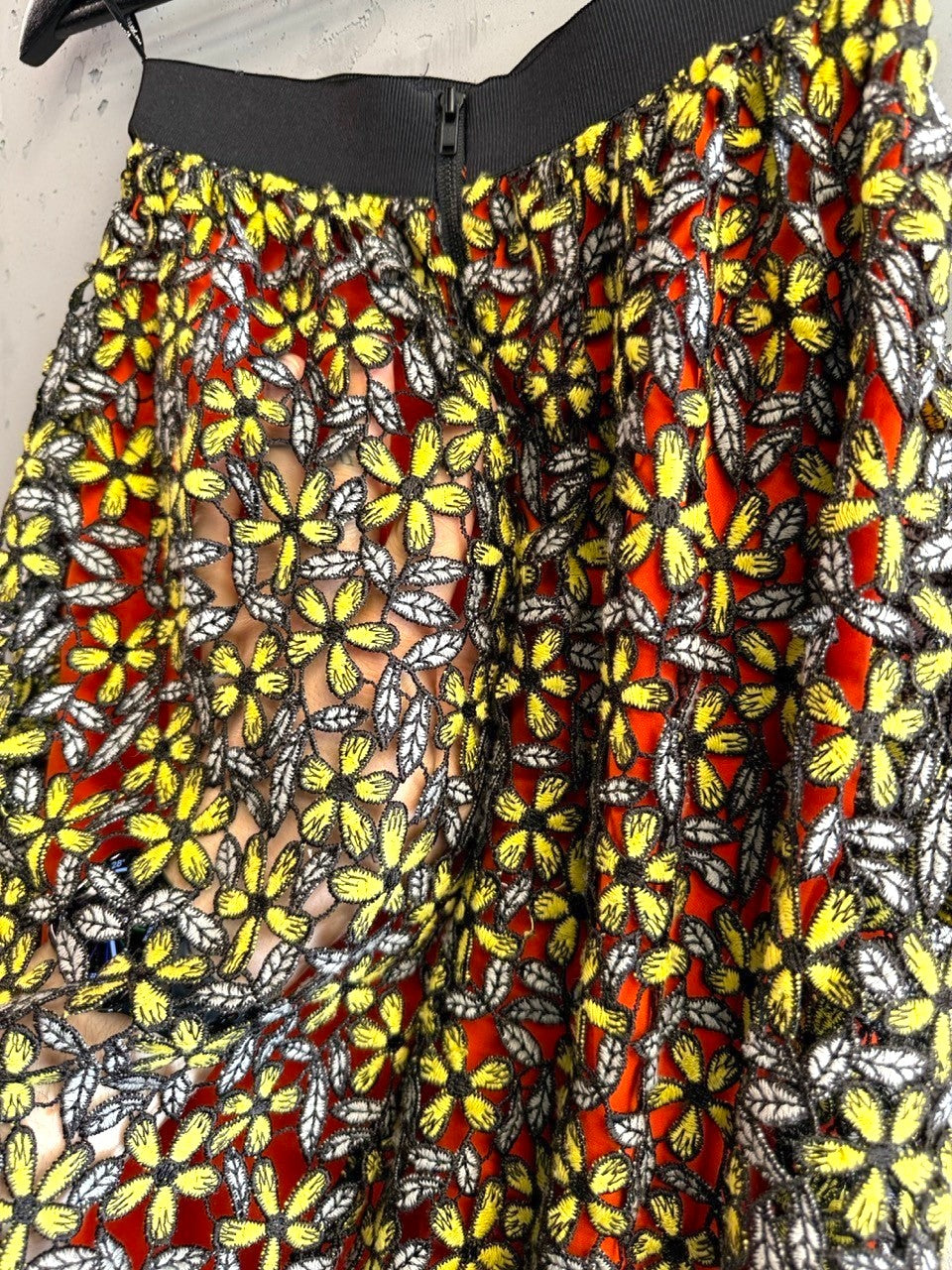 BERLIN VINTAGE CORNER midi skirt with orange lining, floral lace overlay, yellow flowers, grey leaves, and black elastic waistband.