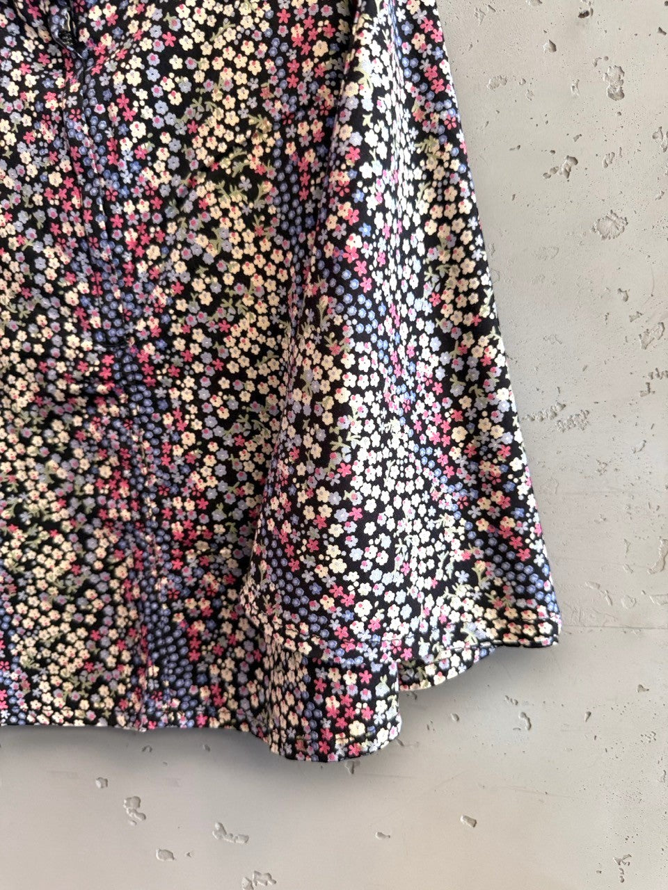 BERLIN VINTAGE CORNER black mini skirt with ditsy floral print in pink, blue, and white. Lightweight fabric, A-line silhouette.