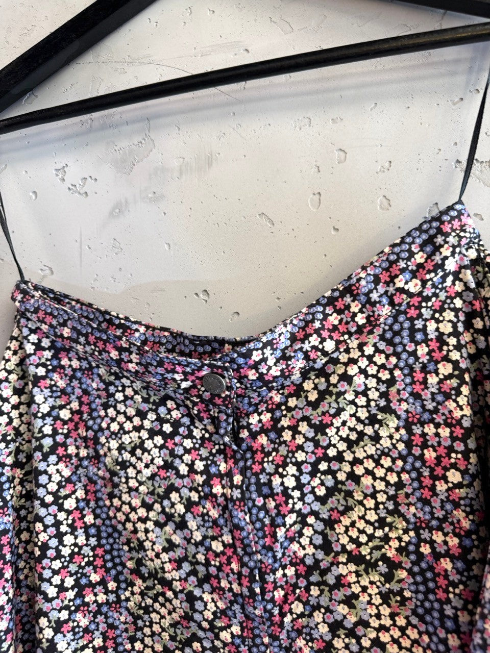 BERLIN VINTAGE CORNER black mini skirt with ditsy floral print in pink, blue, and white. Features a button closure.