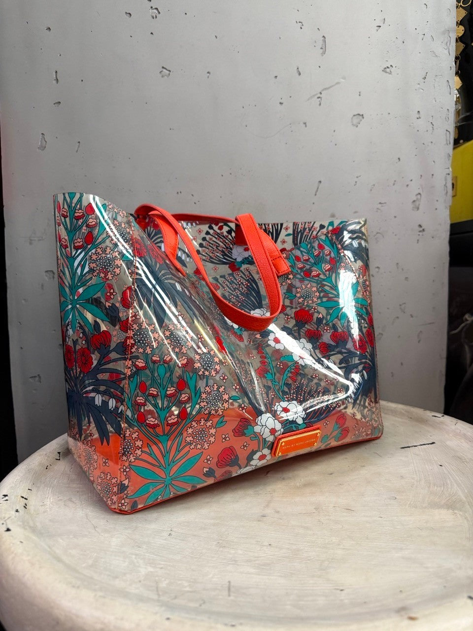 BERLIN VINTAGE CORNER Marc by Marc Jacobs transparent PVC tote with red, teal, and white floral print and orange trim.