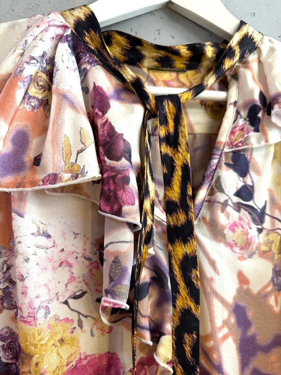 BERLIN VINTAGE CORNER floral print blouse with ruffle neck, tie front, and leopard print accents. Creamy ivory with purple, pink, orange flowers.