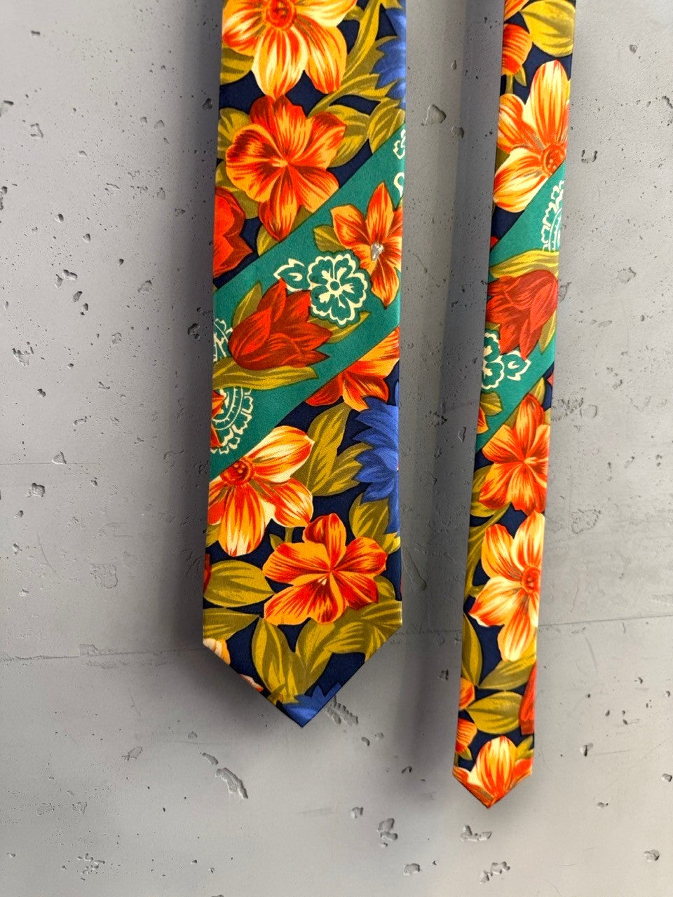 BERLIN VINTAGE CORNER navy floral tie with orange, red, and green blossoms and diagonal green bands with paisley motifs.