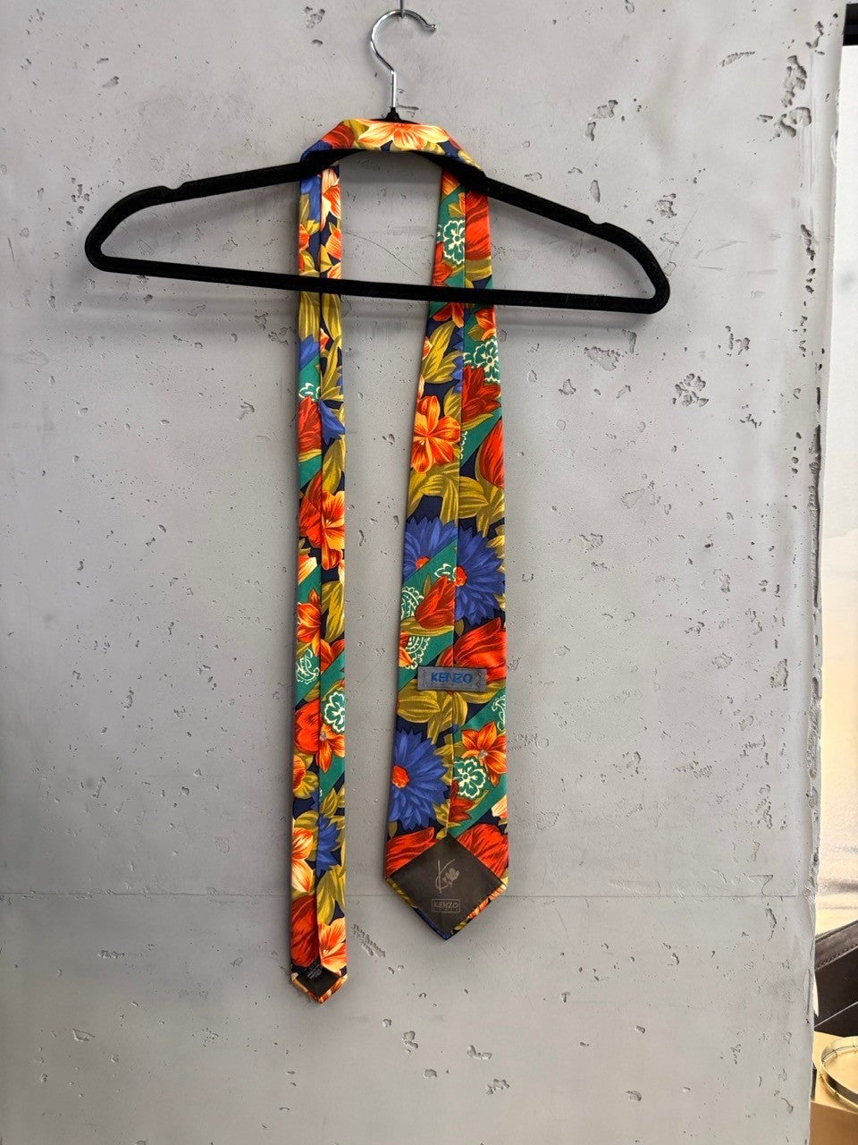 BERLIN VINTAGE CORNER navy tie with bold orange, red, and blue floral pattern and green leaves. Diagonal bands add detail.