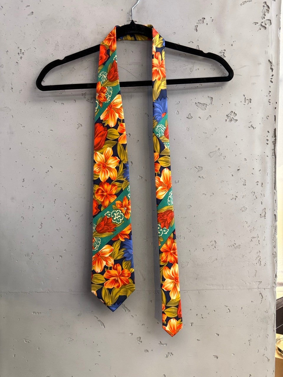 BERLIN VINTAGE CORNER navy tie with bold orange, red, and blue floral pattern and green diagonal stripes.