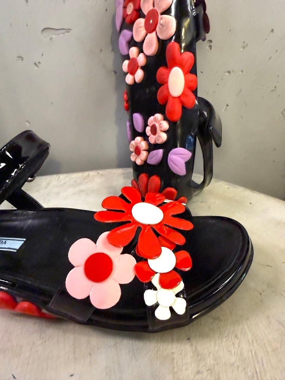 BERLIN VINTAGE CORNER black jelly sandals with red, pink, and purple flower embellishments and lilac leaves.