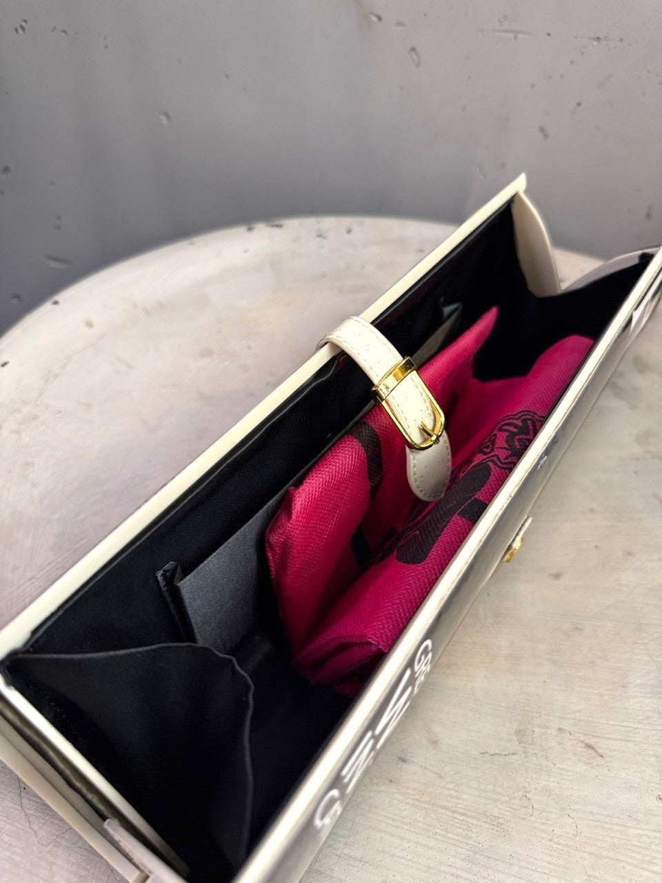 BERLIN VINTAGE CORNER hard shell clutch bag with graphic print, cream strap, gold buckle, and black lined interior.