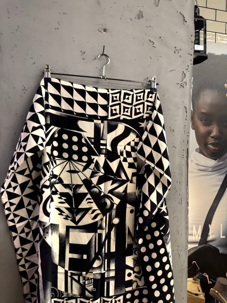 BERLIN VINTAGE CORNER black and white silk scarf with geometric, polka dot, and abstract patterns hanging on a rack.