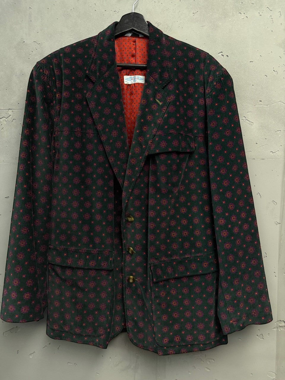 BERLIN VINTAGE CORNER deep green corduroy blazer with red geometric print, two-button closure, and flap pockets.