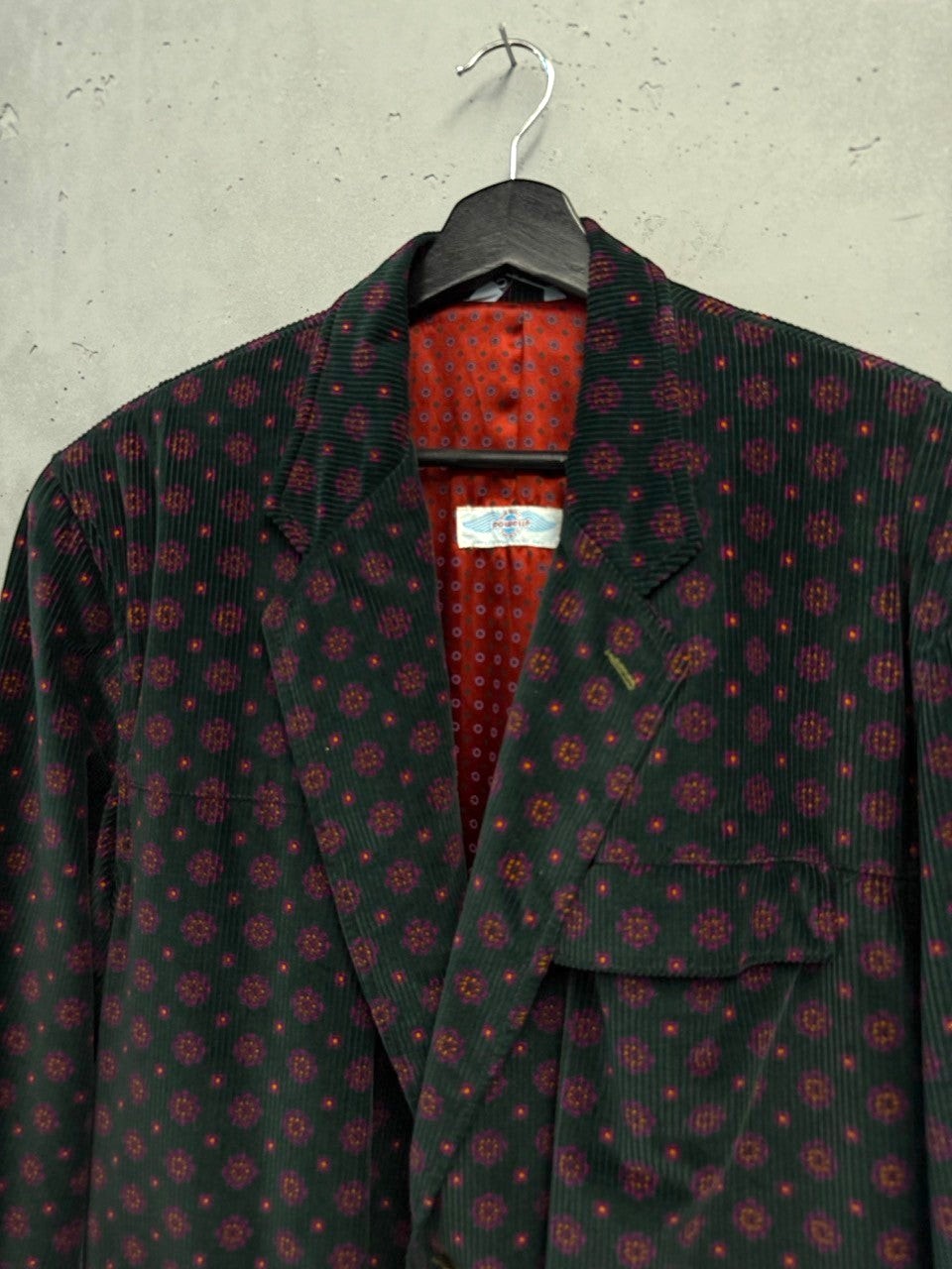 BERLIN VINTAGE CORNER deep green corduroy blazer with all-over geometric print and red lining. Features flap pockets and two-button closure.