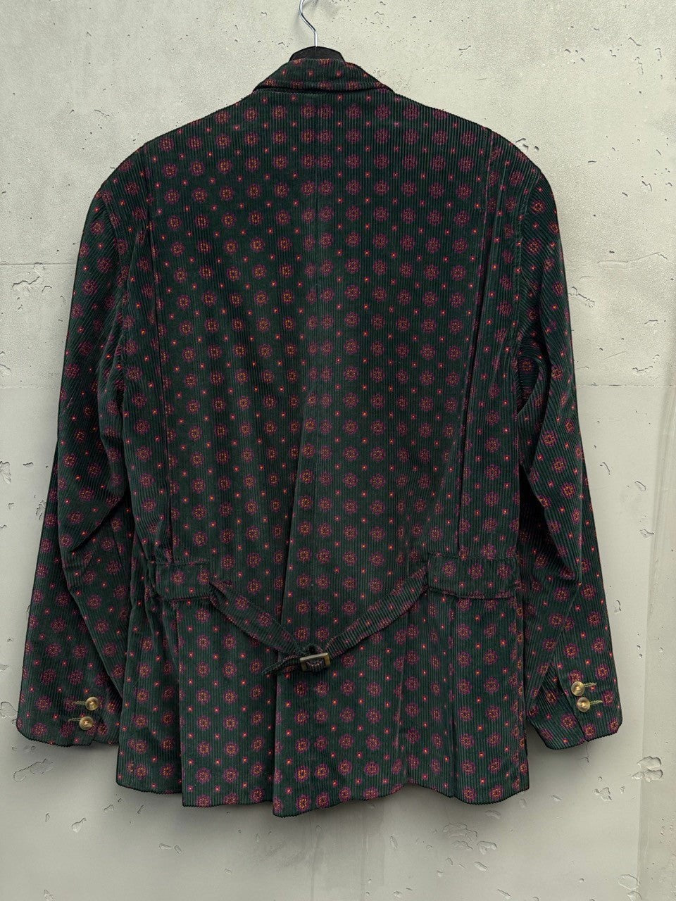 BERLIN VINTAGE CORNER dark green corduroy blazer with all-over geometric print in red. Features a back belt and button cuffs.