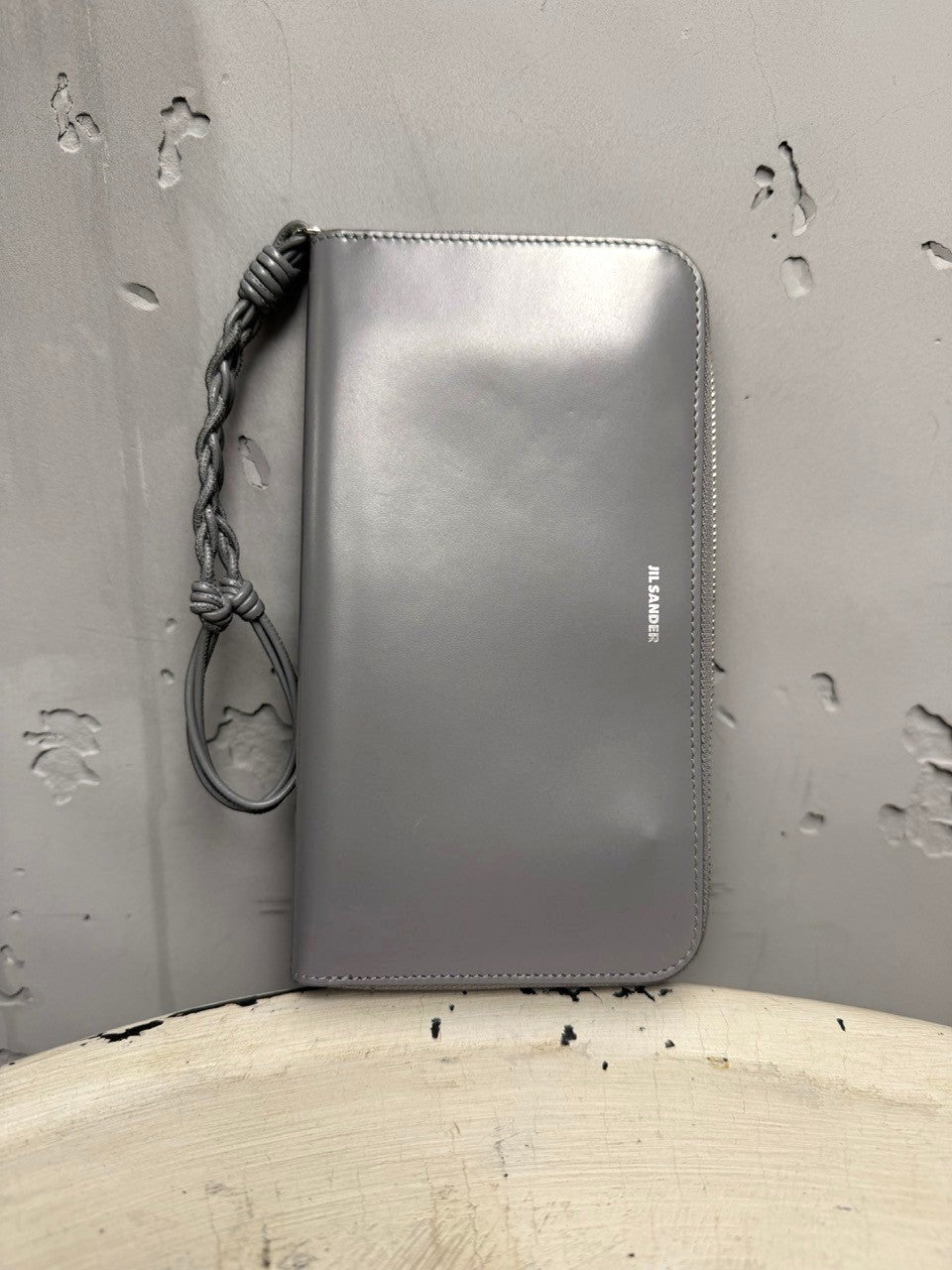 BERLIN VINTAGE CORNER grey leather zip-around wallet with braided wrist strap and embossed logo.