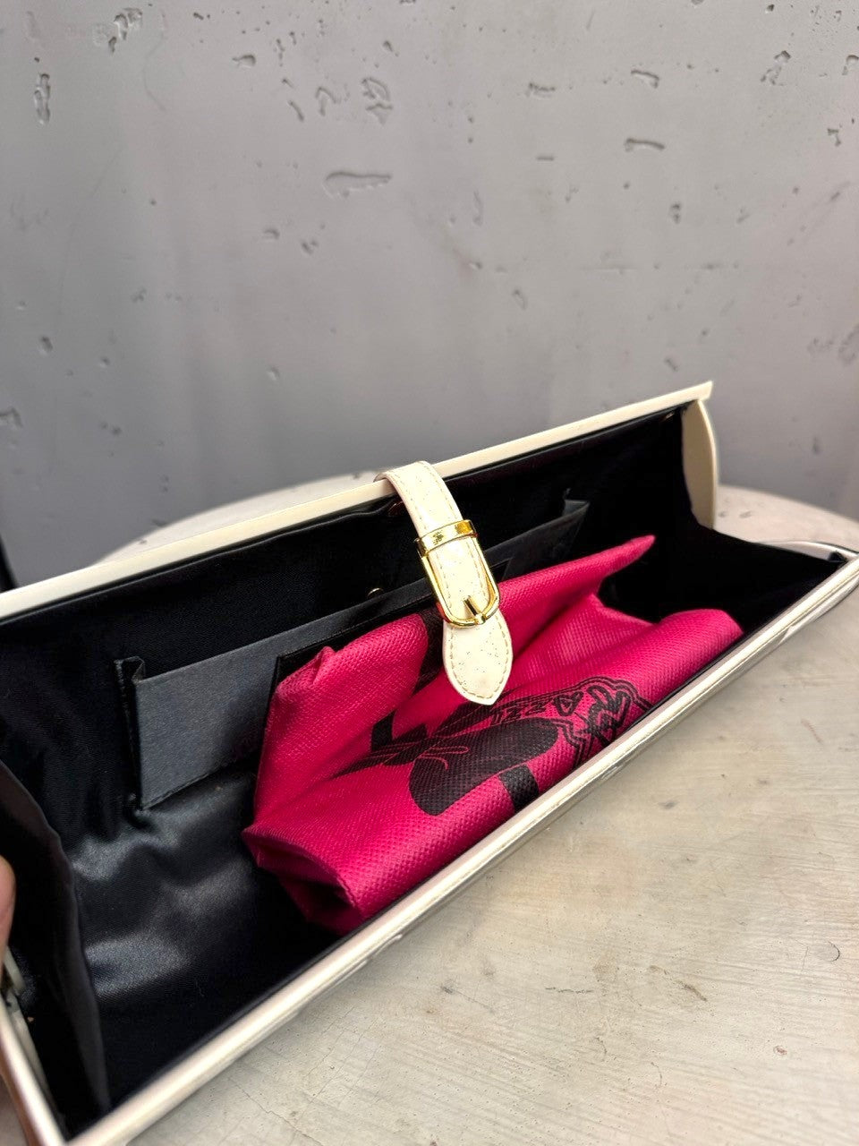 BERLIN VINTAGE CORNER hard shell clutch bag with black interior, cream strap, gold buckle, and pink graphic insert.