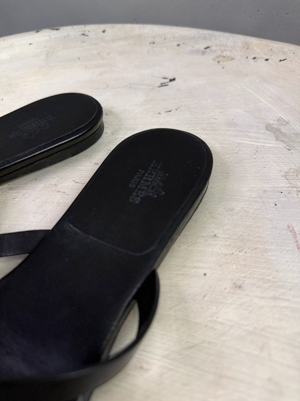 BERLIN VINTAGE CORNER black leather HERMÈS PARIS thong sandals with embossed logo on the footbed