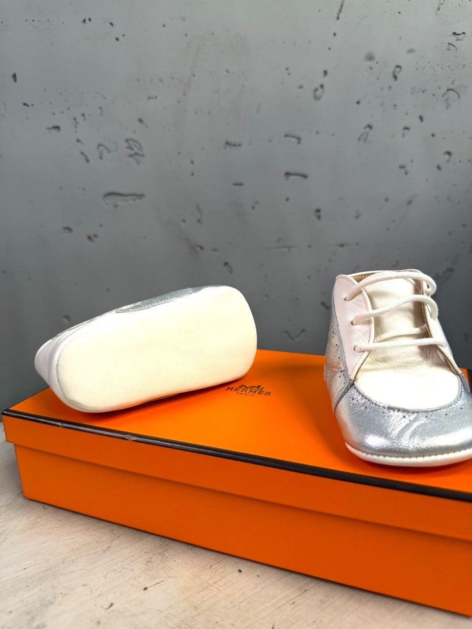 BERLIN VINTAGE CORNER Hermès infant lambskin shoes in white and metallic silver with wing motif on orange box