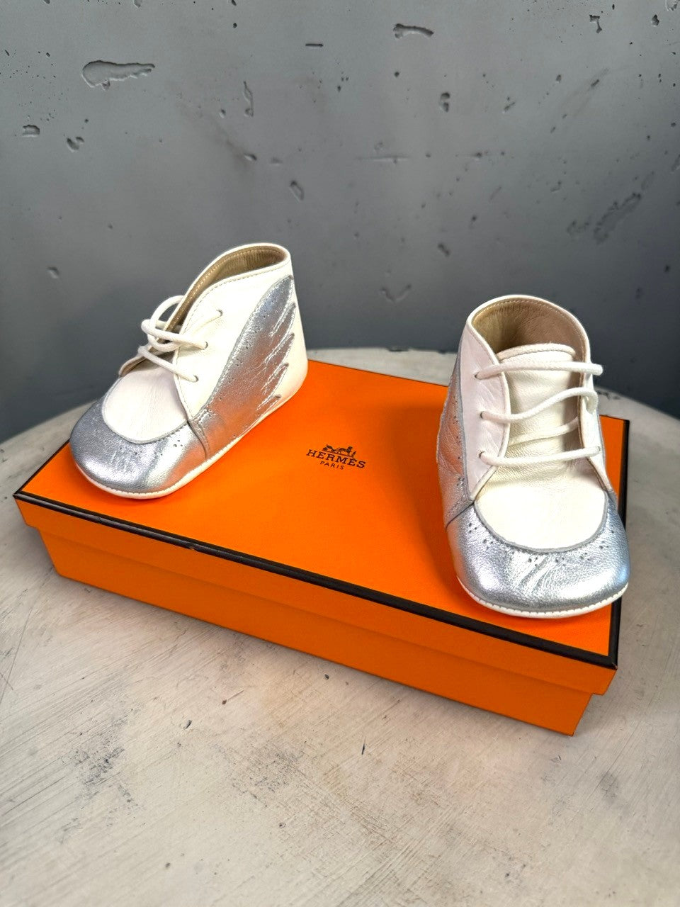 BERLIN VINTAGE CORNER Hermès infant lambskin lace-up shoes in white and metallic silver with wing side motifs.