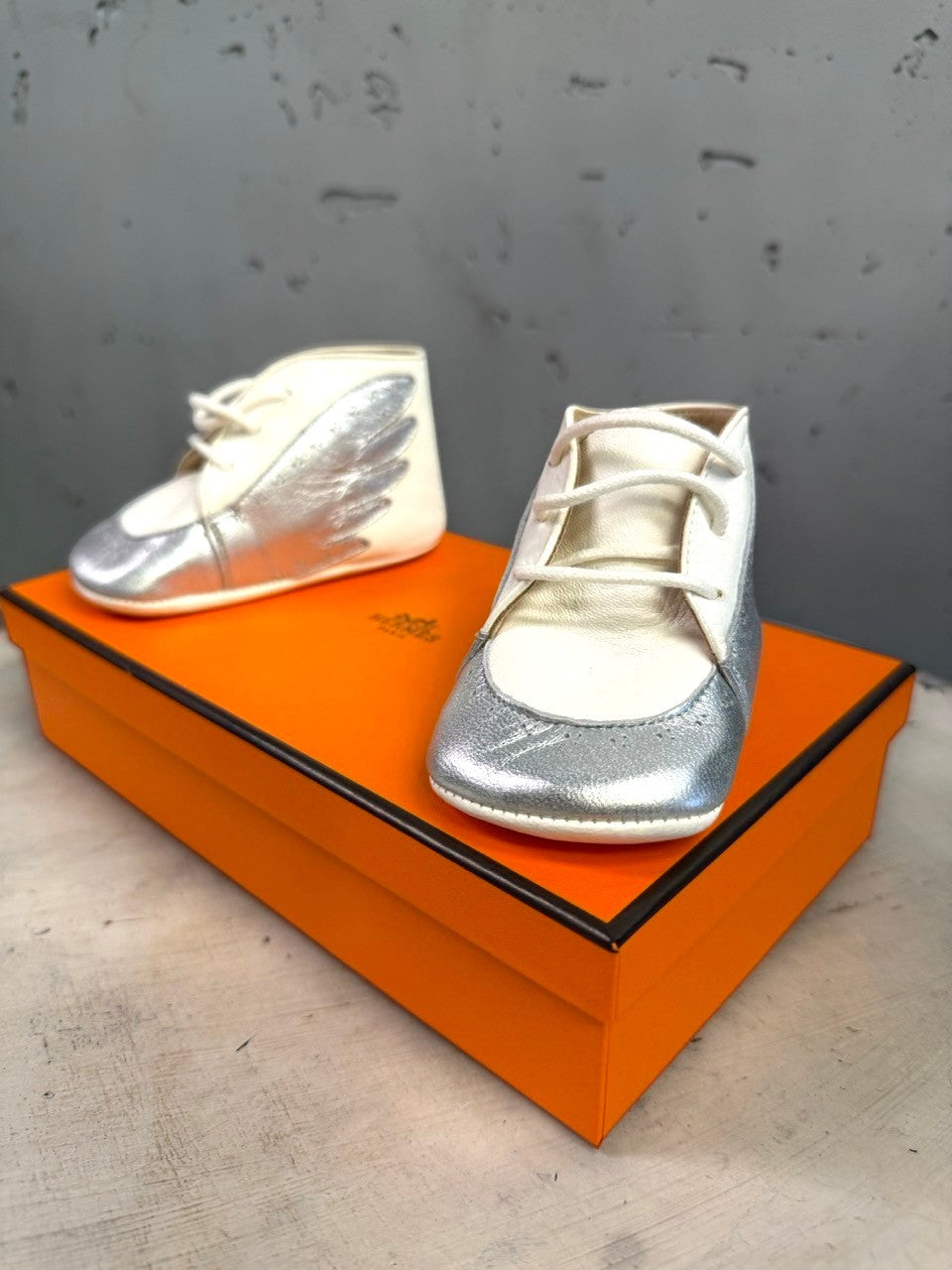 BERLIN VINTAGE CORNER Hermès infant leather lace-up shoes in white and metallic silver with wing motif on orange box