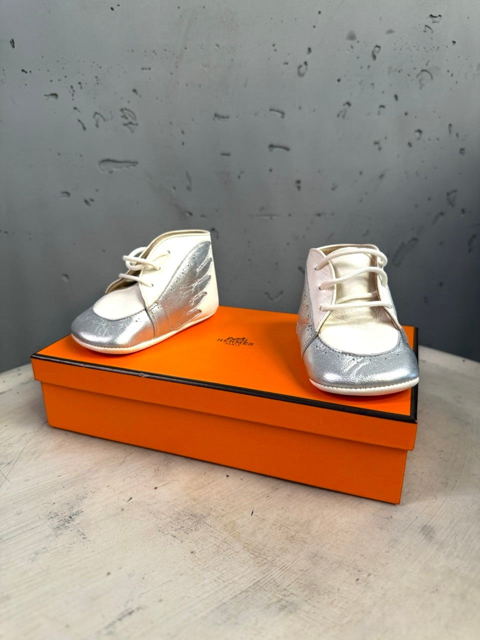 BERLIN VINTAGE CORNER Hermès infant lambskin lace-up shoes in white and metallic silver with wing side detail on box
