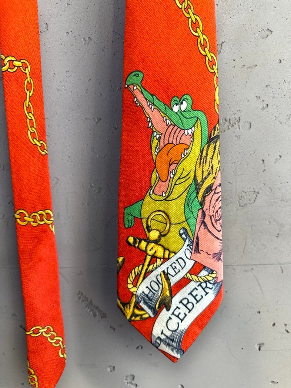 BERLIN VINTAGE CORNER ICEBERG orange necktie featuring a whimsical crocodile, gold chain, and floral graphic print.
