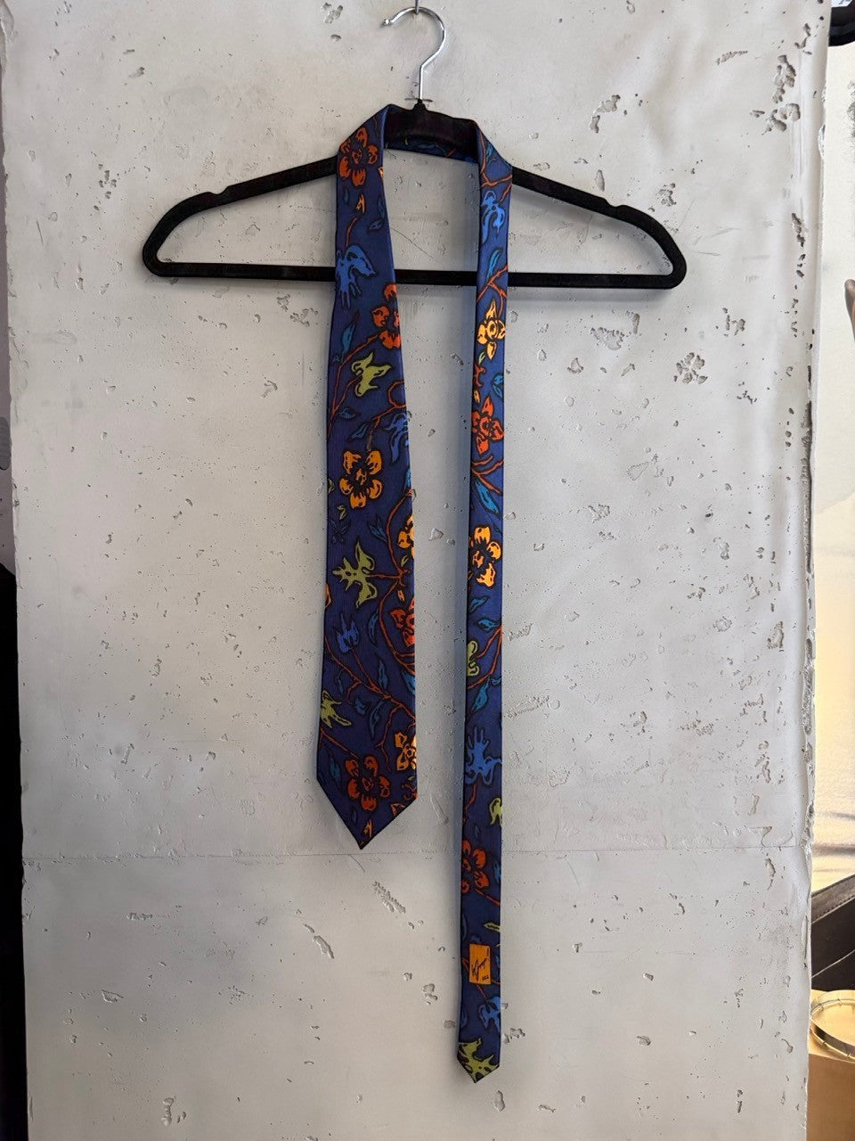 BERLIN VINTAGE CORNER JOOP! blue necktie featuring an artistic floral pattern in orange, yellow, and teal on a hanger.