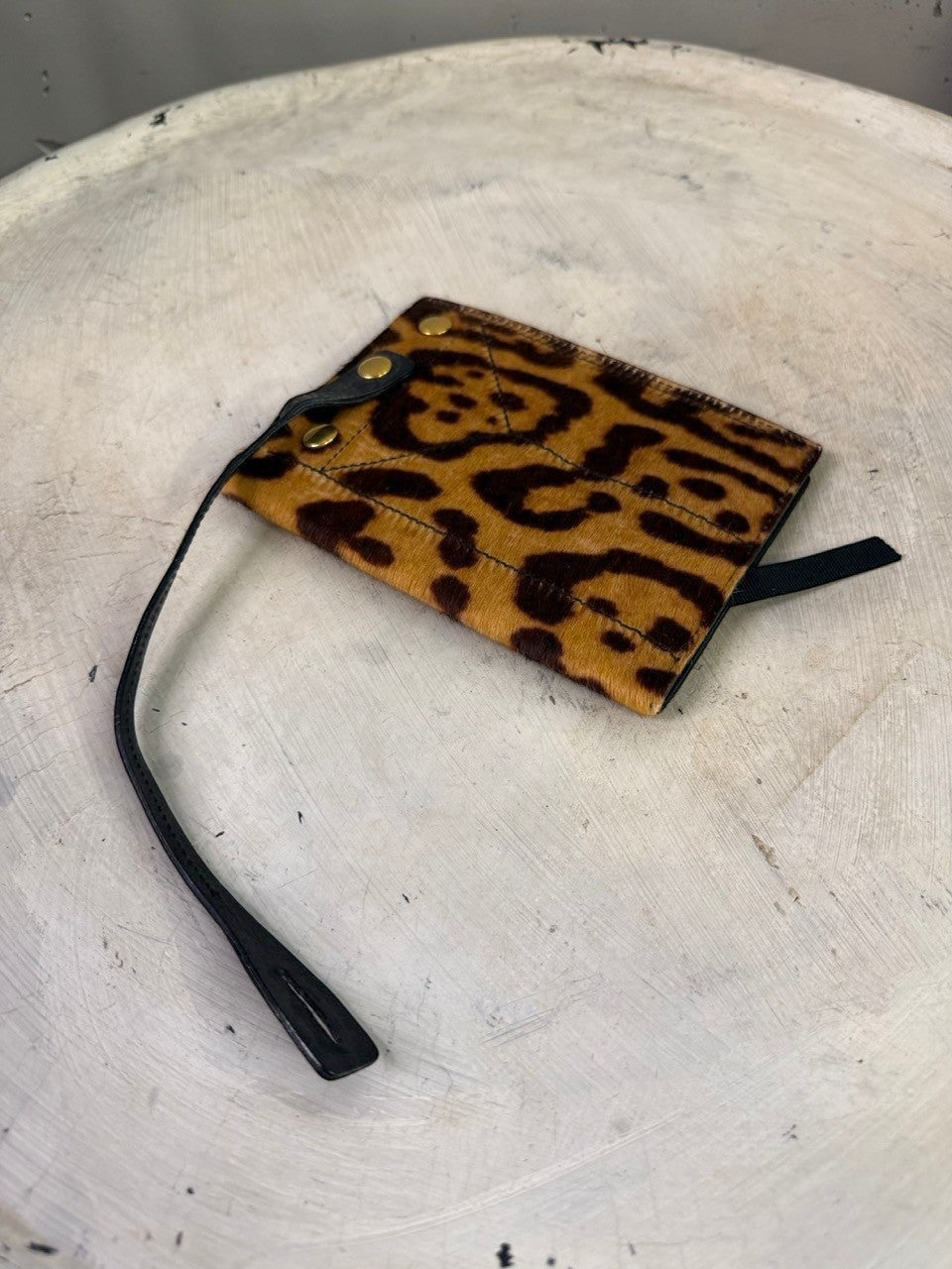 BERLIN VINTAGE CORNER leopard print calf hair cardholder with black leather strap and snap closure.