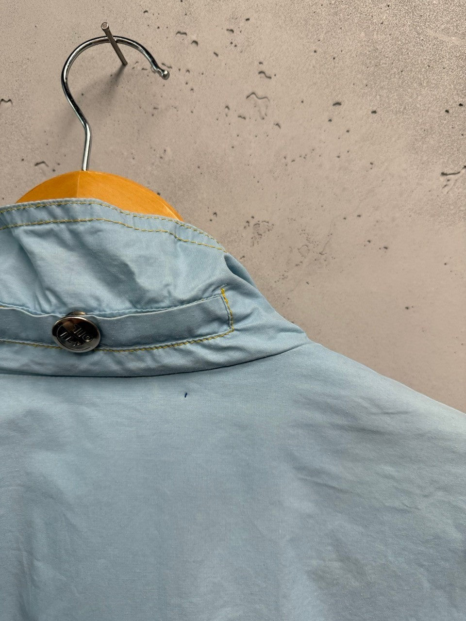 BERLIN VINTAGE CORNER light blue lightweight windbreaker jacket with yellow stitching and a snap button detail.