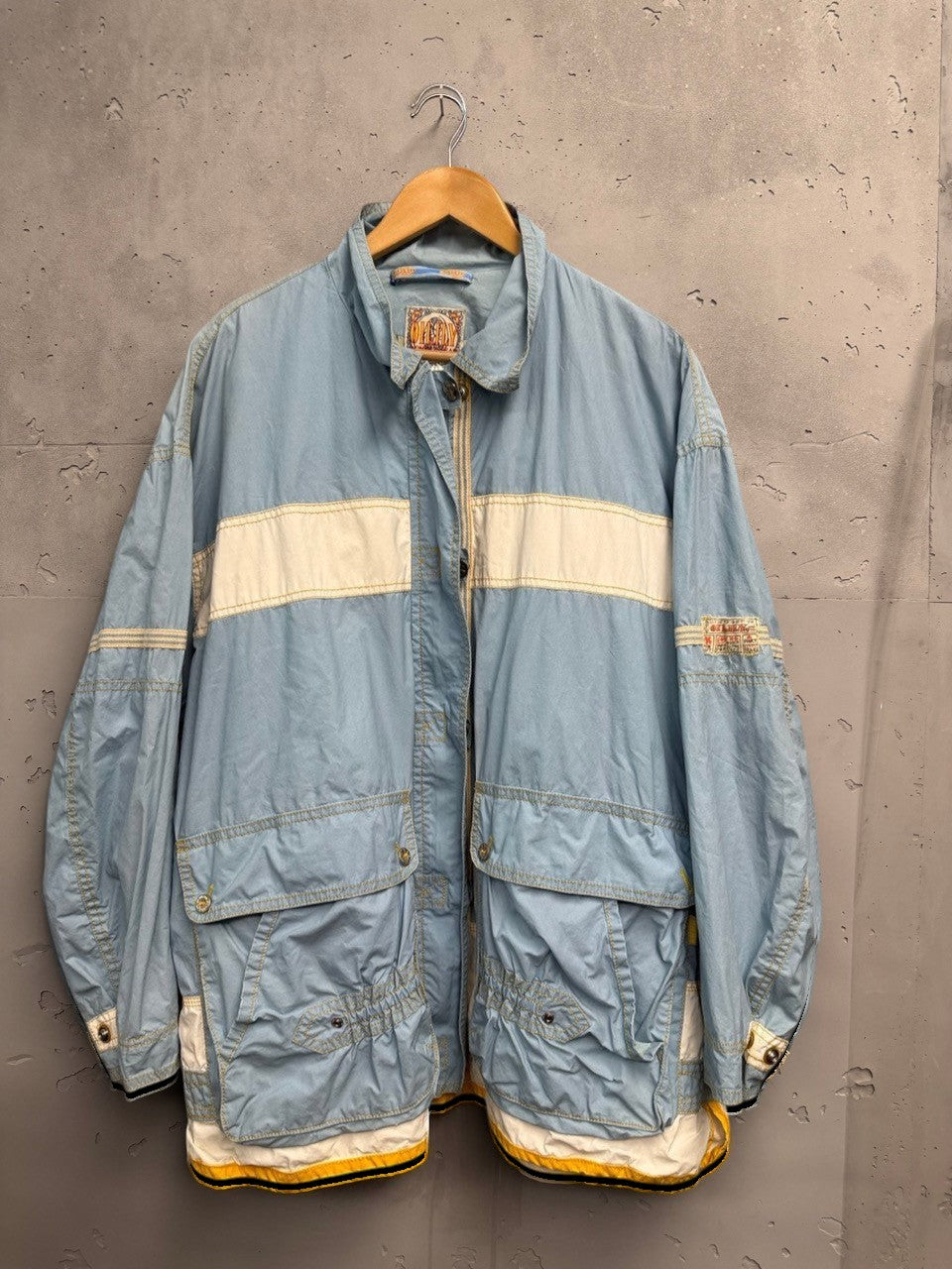 BERLIN VINTAGE CORNER light blue windbreaker jacket with white stripe detail, snap pockets, and full zip. Lightweight fabric with plaid lining.