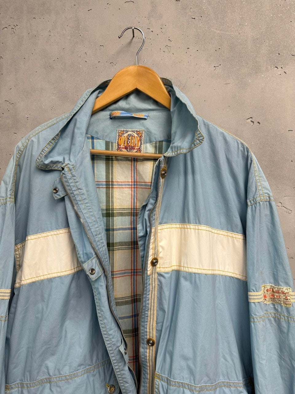 BERLIN VINTAGE CORNER light blue lightweight windbreaker jacket with plaid lining, white stripes, and snap pockets.