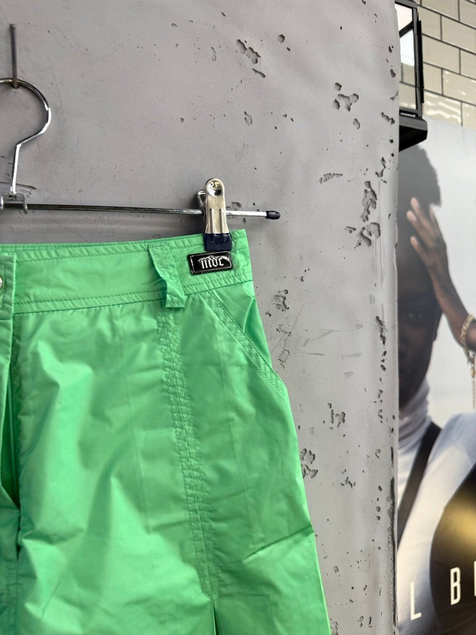 BERLIN VINTAGE CORNER lime green pleated mini skirt with belt loops and side pockets, hanging on a metal clip hanger.